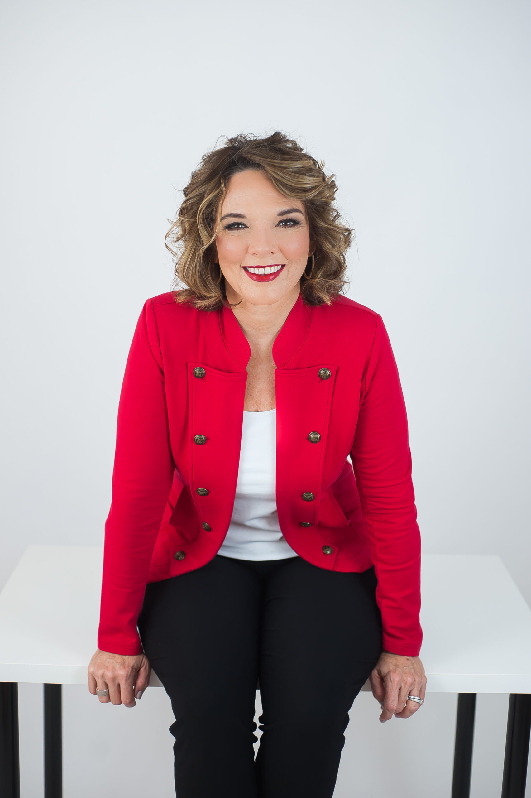Colene Rogers Seated Wearing A Red Jacket